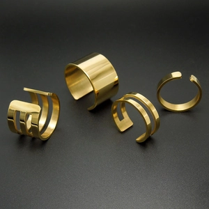 Set of four 18k rose gold plated stainless steel open rings on black sand background