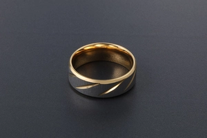 Macro detail of men's titanium ring with silver matte grooves and gold polished interior