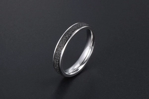 Détail de la bague en acier argenté avec une finition sablée noire mate texturée