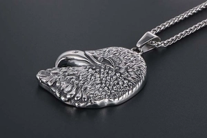 Macro view of detailed eagle head pendant in silver stainless steel with wheat chain