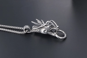 Detalle macro del colgante de cabeza de dragón vintage con escamas y anillo de plata