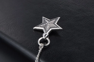 Macro detail of silver pentagram star pendant with radial texture on black leather