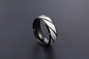 Close-up of black titanium steel ring with silver brushed diagonal stripes for men