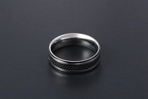 Detail of titanium steel ring with black dotted pattern and polished silver inner band