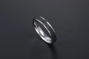 Détail de la texture sablée noire mate et des bords argentés polis sur une bague