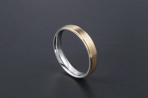 Detail of gold honeycomb texture and polished steel edges on a minimalist band ring