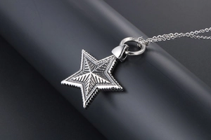 Close-up of silver pentagram pendant with radial textures and serrated edges on chain