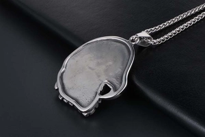 Macro shot of silver eagle head pendant showing matte texture and polished edges