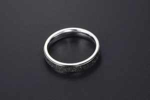 Détail macro d'une bague en acier argenté avec incrustation en sable noir mat