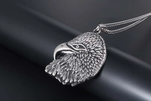 Detailed close-up of eagle head pendant showing intricate feather texture and steel chain