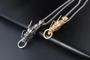 Detalle de los colgantes de cabeza de dragón en oro y plata con cadenas spiga en cuero