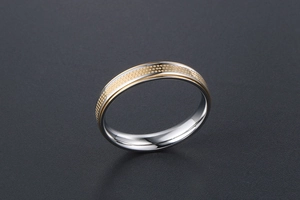 Detailed macro view of two-tone steel ring with golden dotted pattern textures