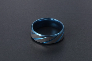 Detailed view of two-tone men's ring with blue spiral groove and brushed steel finish