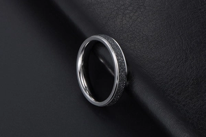 Vue macro d'une bague argentée avec incrustation sable noir mat et texture étoilée
