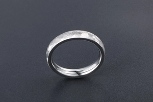 Close-up of silver steel ring featuring hammered texture and polished inner band