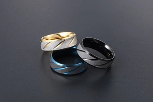Macro detail of stacked brushed titanium steel rings in gold, black, and blue finishes