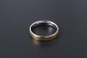 Macro detail of titanium steel ring featuring gold dotted texture and silver polished edges