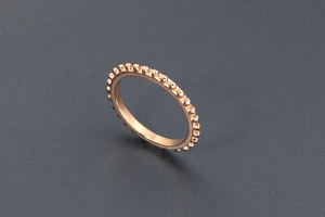 Makro-Detail eines roségoldenen Kugelrings mit minimalistischem Perlen-Design auf grauem Grund