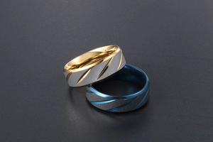 Detail of brushed titanium steel rings with gold and blue plated grooved accents