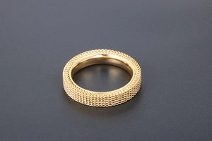 Macro detail of golden mesh texture and polished inner band on a titanium steel ring