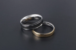Macro shot of two titanium steel rings with black and gold dotted industrial textures