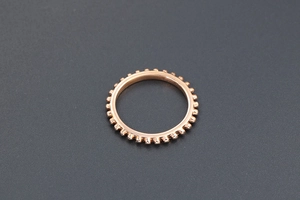 Detailaufnahme eines minimalistischen Kugelrings in Roségold auf dunkelgrauem Grund