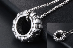 Détail macro du pendentif pneu argenté avec gravure vintage et chaîne en métal robuste