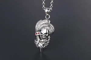Détails du pendentif crâne punk avec yeux en pierres rouges et textures de feuilles