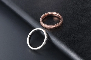 Macro shot of silver and rose gold hammered texture titanium rings on black leather