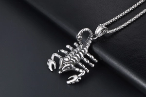 Close-up of a silver stainless steel scorpion pendant on a heavy link chain necklace