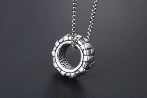 Détail macro du pendentif pneu industriel avec découpe nid d'abeille et collier de luxe