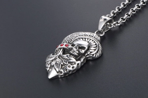 Détail macro du pendentif crâne punk avec strass rouges et textures de feuilles ciselées
