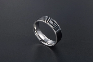 Détail d'une bague en titane argentée avec rayures noires et cristal central serti