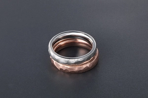 Macro shot of silver and rose gold hammered finish titanium rings on black background