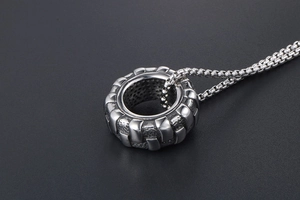 Détails macro du pendentif pneu industriel avec finition vieillie et chaîne à mailles carrées