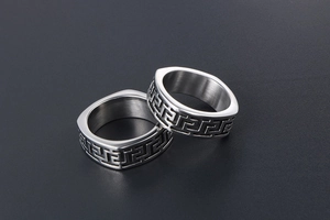Macro detail of silver titanium steel rings featuring vintage black Greek key patterns