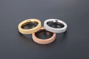 Detailed view of tricolor mesh textured rings in gold, silver, and rose gold steel