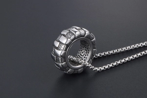 Gros plan du pendentif pneu vintage au fini industriel noir avec une chaîne box