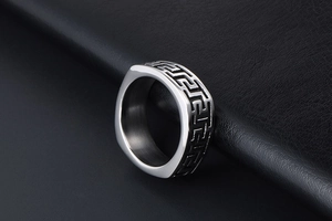 Macro shot of silver titanium steel signet ring with Greek meander pattern engraving