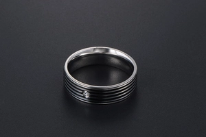 Gros plan d'une bague en acier titane avec rayures noires et un seul diamant scintillant