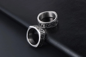 Detailed macro of vintage titanium steel rings with Greek fret patterns on black leather