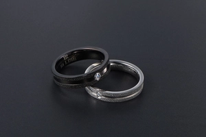 Macro detail of matte 316L stainless steel couple rings with polished inlay and zircon