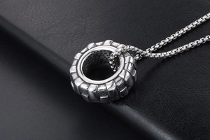 Détail du pendentif pneu argenté avec surface texturée et chaîne box en acier inoxydable