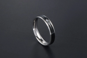 Détail d'une bague en acier titane avec insert noir et un accent de diamant au centre