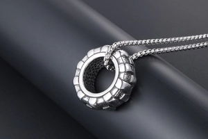 Vue macro d'un pendentif pneu en acier inoxydable argenté avec textures industrielles
