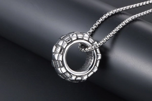 Vue macro du pendentif industriel en acier inoxydable motif pneu sur socle sombre