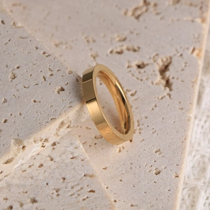 Bague de couple minimaliste en acier inoxydable doré sur fond de pierre de travertin
