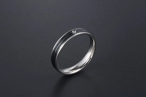 Détail d'une bague en acier titane argenté avec des rayures noires et un petit diamant