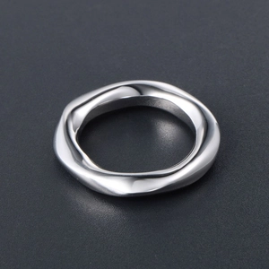 Bague minimaliste en acier titane argenté aux lignes irrégulières sur fond noir mat