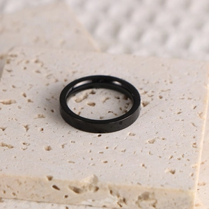 Vue macro d'une bague noire lisse minimaliste sur un support en pierre naturelle